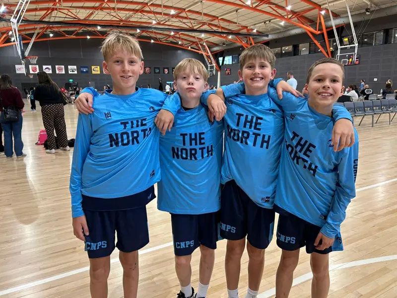 Four boys in matching team shirts at a basketball stadium