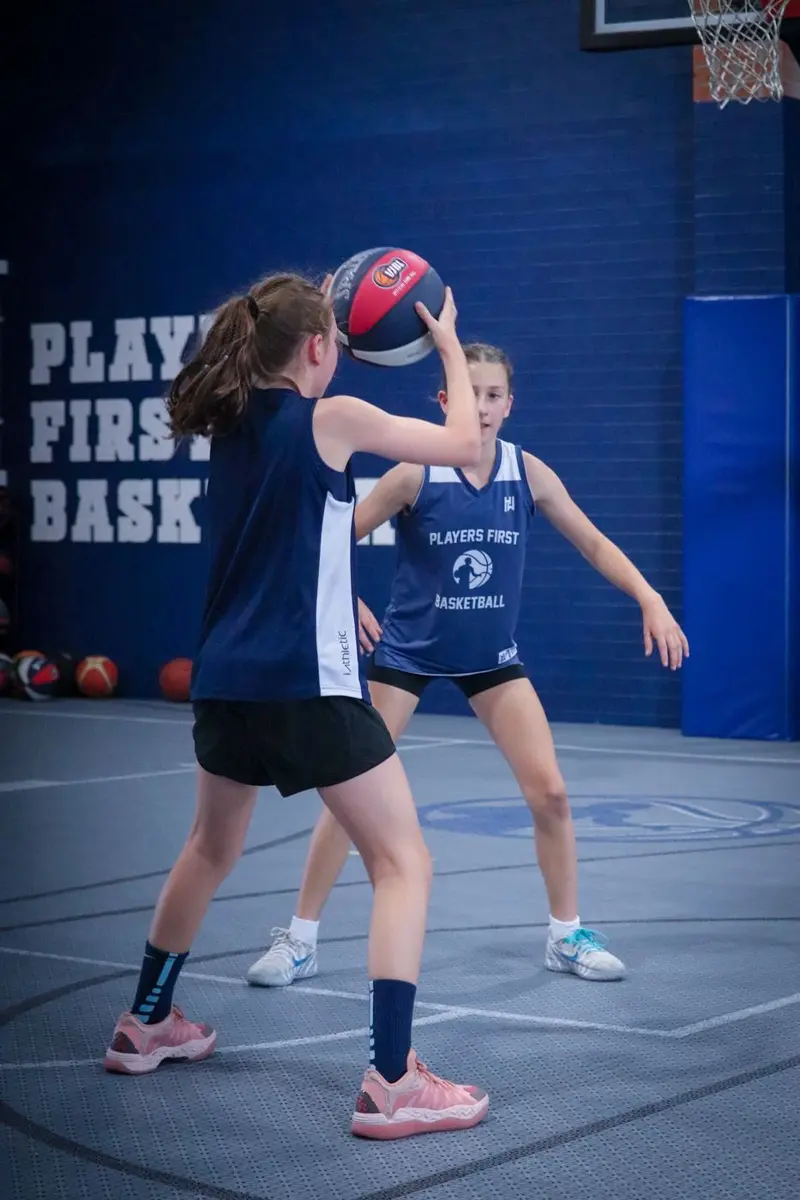 Two teenage girls practising passing and defence