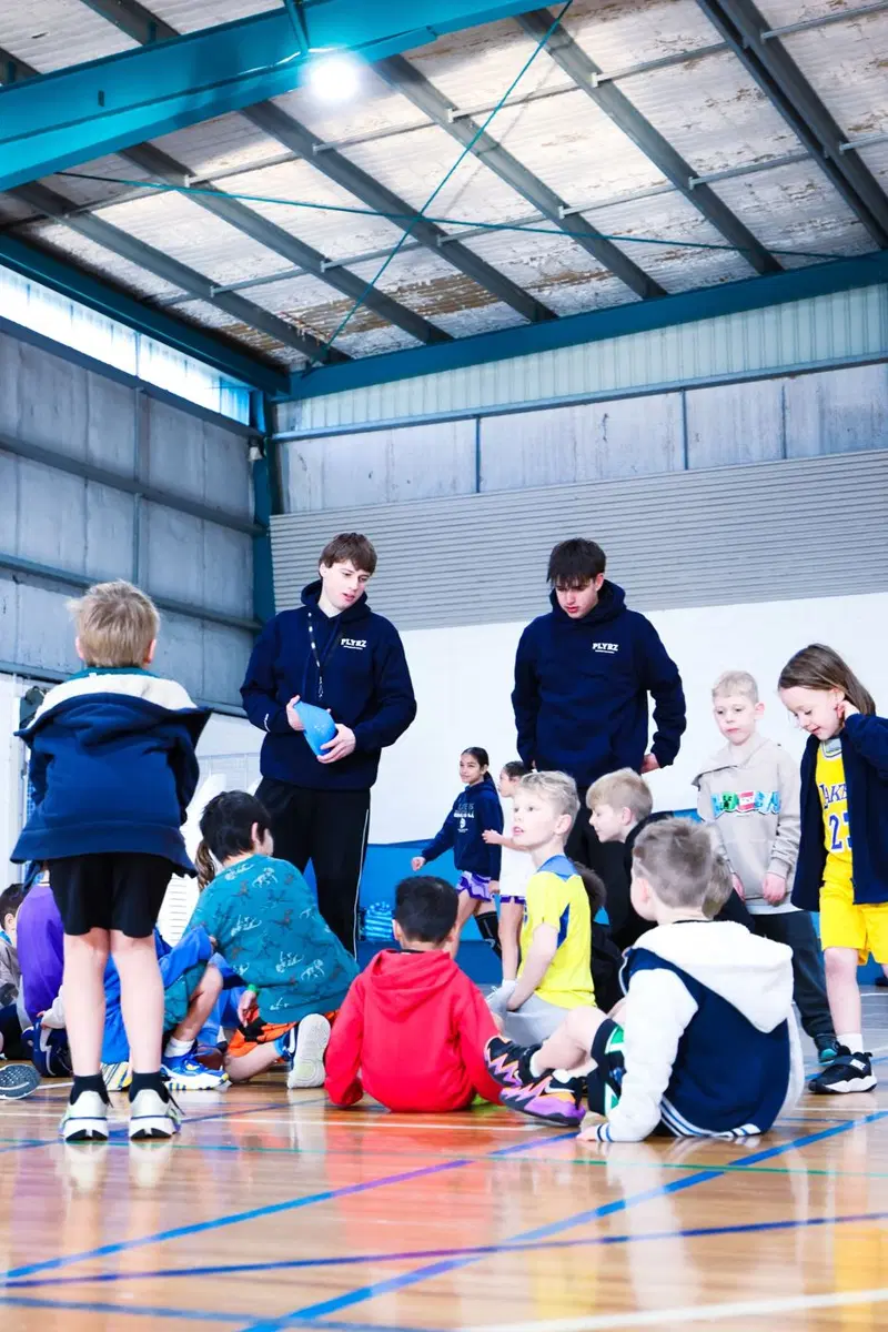 Coaches talking with a group of young kids on court