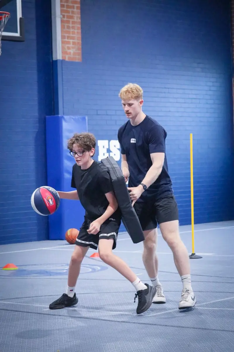 A coach working with a player on dribbling